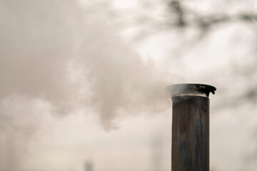 Smoke comes from black offset smoker grill in home backyard, family patio, barbeque party on open...