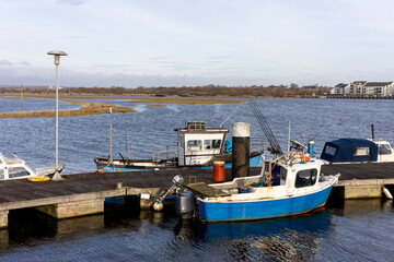 Fototapeta premium Small Fishing Boats Moored at a Dock in a Calm Harbor With Out Board Motors and Fishing Rods