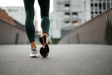 Close-up rear view of athlete's feet in sneakers, one of which she has placed on her toe