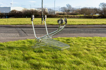 Abandoned Metal Shopping Cart on Public Grass Verge Beside Buildings