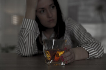 Alcohol addiction. Woman with glass of whiskey at table, selective focus