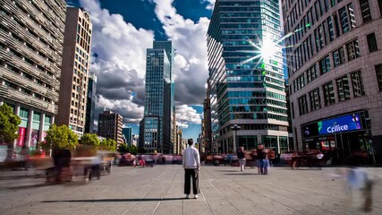 man stands still in a modern city square surrounded by towering glass skyscrapers and blurred pedestrians under a bright sky, symbolizing urban life