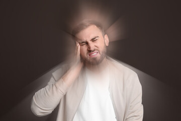 Man suffering from headache and dizziness on dark brown background