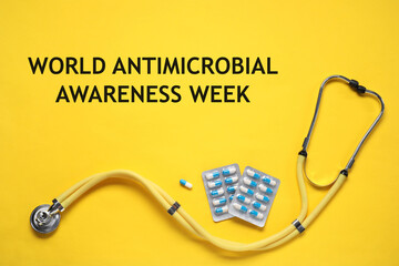 World antimicrobial awareness week. PIlls and stethoscope on yellow background, flat lay