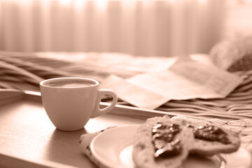 Morning coffee and sandwiches on tray in bedroom, toned in mocha mousse shade. Trendy color of 2025...