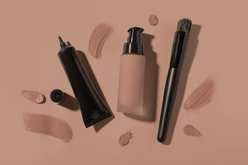 Liquid foundations in mocha mousse shades and makeup brush on dark beige background, flat lay. Trendy color of 2025 year