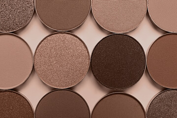 Eyeshadows in mocha mousse shades on dark beige background, flat lay. Trendy color of 2025 year