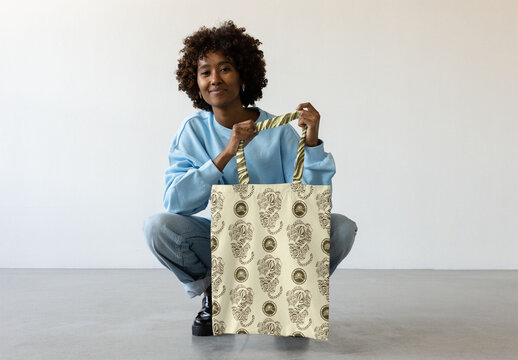 Afro black woman poses with a blank tote bag. PSD mockup