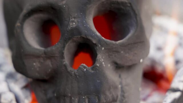 Flaming Skull With Glowing Eyes Sitting on Hot Embers Slow Motion