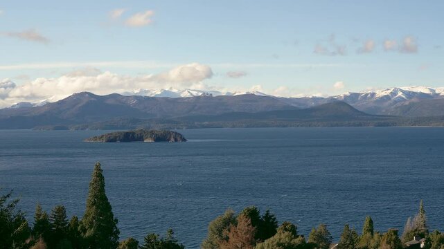 Small island on deep blue Nahuel Huapi Lake with distant Andes