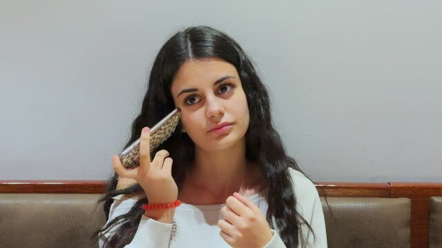 Young woman listening to voice message in restaurant booth