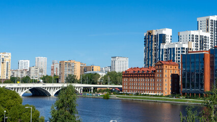 Obraz premium View of Makarovsky quarter and bridge on embankment of city pond, Iset River, Yekaterinburg, Russia. View from Boris Yeltsin Presidential Center
