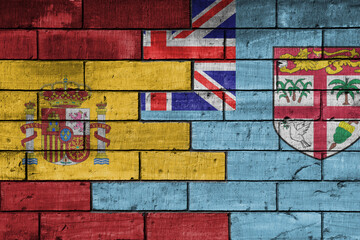 colourful painted big flag of spain and flag of Fiji on a massive old brick wall background. concept