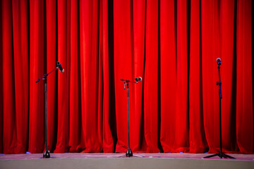 a stage with microphones and red curtains