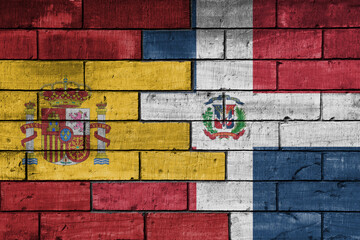 colourful painted big flag of spain and flag of dominican republic on a massive old brick wall...