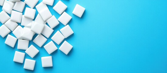 White sugar cubes scattered on a bright blue background with copy space for text.