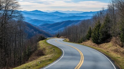 Fototapeta premium Winding mountain road with soft blue misty layers of hills in the background and trees along the roadside Copy Space
