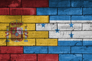 Fototapeta premium colourful painted big flag of spain and flag of honduras on a massive old brick wall background. concept