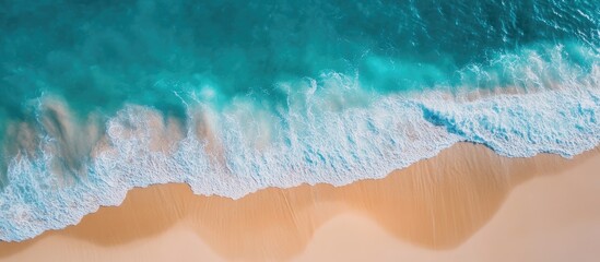 Obraz premium Serene ocean beach background with vibrant turquoise water and soft sandy shoreline ideal for vacation banners and promotional text space