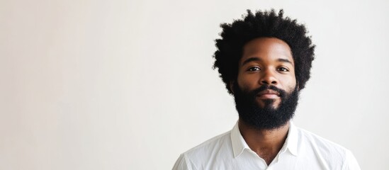 Fototapeta premium Bearded man with afro hairstyle in a white shirt against a neutral background perfect for adding text or promotional content