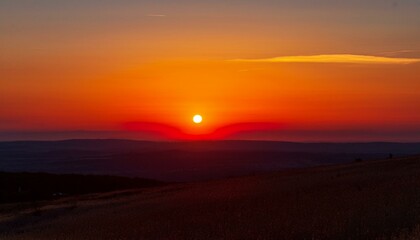 Obraz premium 멀리 수평선 위로 떠오르는 선명한 일출, 붉고 따뜻한 색감의 태양