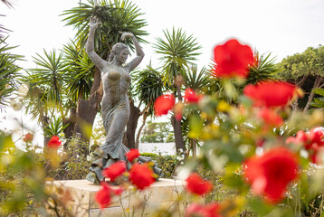 Rose flowers framing dynamic statue in honour of Flamenco singer and dancer Lola Flores. Actress memorial sculpture