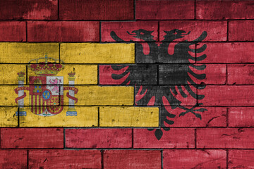 colourful painted big flag of spain and flag of albania on a massive old brick wall background. concept