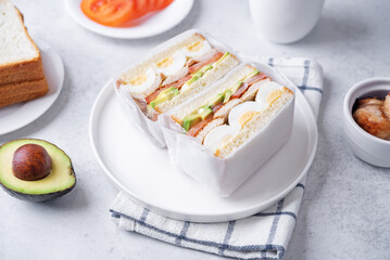 Eggs fired meat avocado tomato sandwiches in a plate