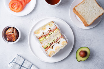 Eggs fired meat avocado tomato sandwiches in a plate