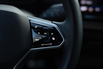 Heated steering wheel control buttons with blurred dashboard in car interior. Heated steering wheel...