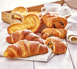 Croissant, palmier i ciastka z czekoladą na drewnianym stole © Jolaya