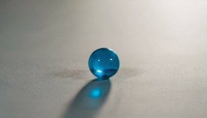 무채색의 회색 배경 위에 하나의 푸른 구슬이 반짝이며 중앙에 놓여 있다. 구슬은 투명한 빛을 반사해 강조된다