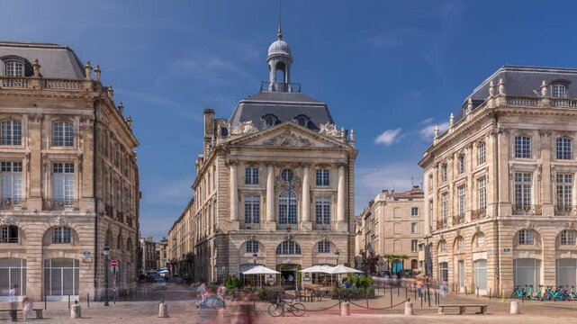 Place de la Bourse timelapse hyperlapse in Bordeaux, France, with restaurants surrounded by classic architecture under a cloudy blue sky. People walking around the main square and central streets