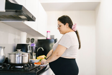 Pregnant colombian woman preparing food in kitchen