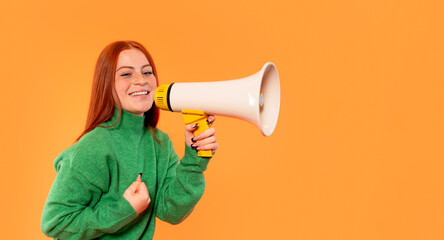 Woman joyfully using megaphone with vibrant orange background in casual green sweater
