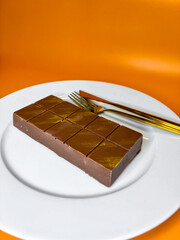 on a plate lies a bar of Dubai chocolate, next to a fork and knife