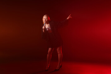 Beautiful singer performing on dark background with red light