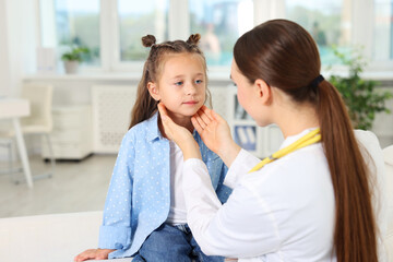 Doctor examining girl's throat in clinic during appointment