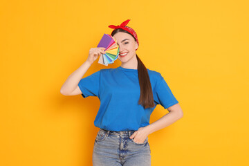 Portrait of young decorator with color palettes on orange background