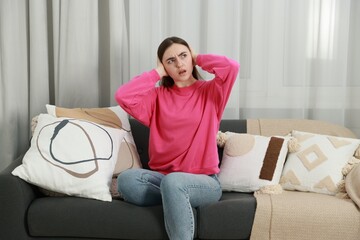 Annoyed woman covering her ears from loud noise at home