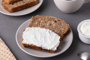 Slices of whole grain bread topped with cream cheese on a plate in a cozy kitchen setting