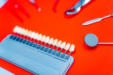 Dental tools and tooth samples. Dental tools and tooth color samples are displayed on a bright red...