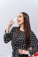 Chic woman with a drink. A woman in a polka dot blouse smiles while sipping water, her long hair...