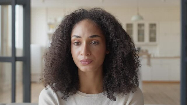 Sad Curly African American Woman Looking Camera in Apartment at Home