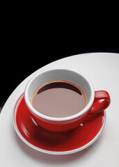 red cup with americano coffee drink. Cafe and restaurant menu. White table and black wall. Space for text. Coffee shop. Coffee addiction