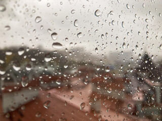 A candid shot of a rainy urban street, viewed through a droplet-patterned window