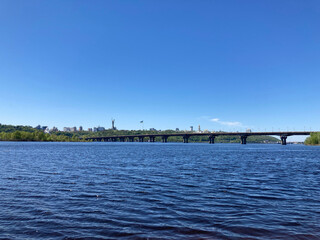 Obraz premium Panoramic photograph of a calm water body with a bridge, possibly a lake or sea near an urban area Clear sky above