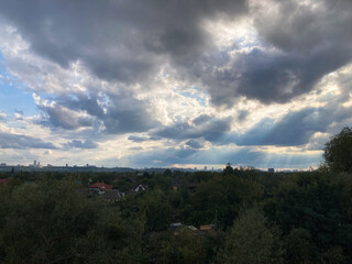 A panoramic, wide-angle shot of an urban landscape with dramatic sunlight streaming through clouds,...
