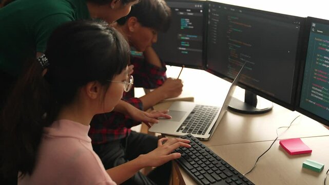 Slow motion back end software developer engineer for computer programming working together on debugging writing computing code, solving complex algorithms display on monitor in office. Burgeoning