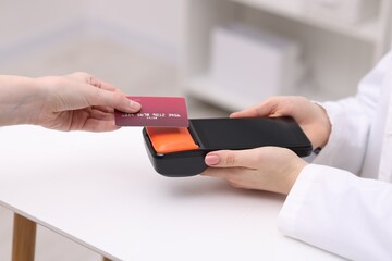 Woman paying with credit card via terminal at counter indoors, closeup